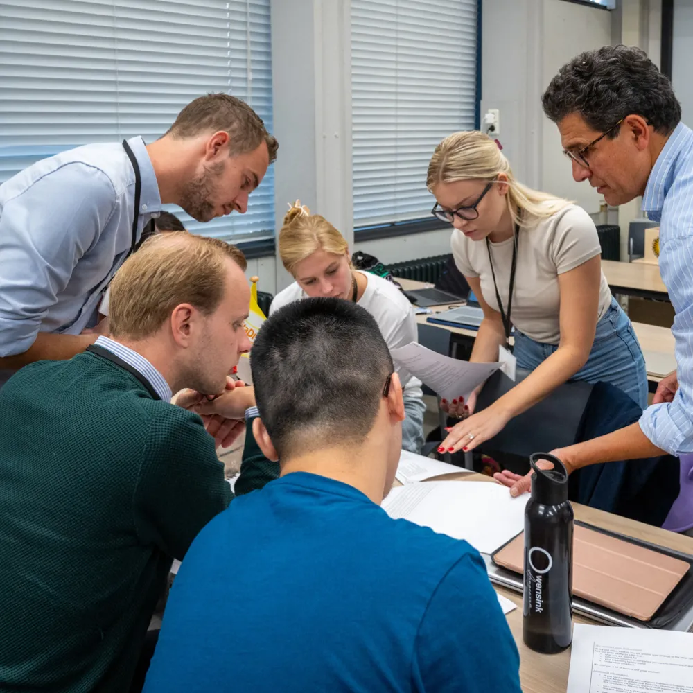 Begeleiders bekijken documenten waar een groep studenten mee aan het werk is.