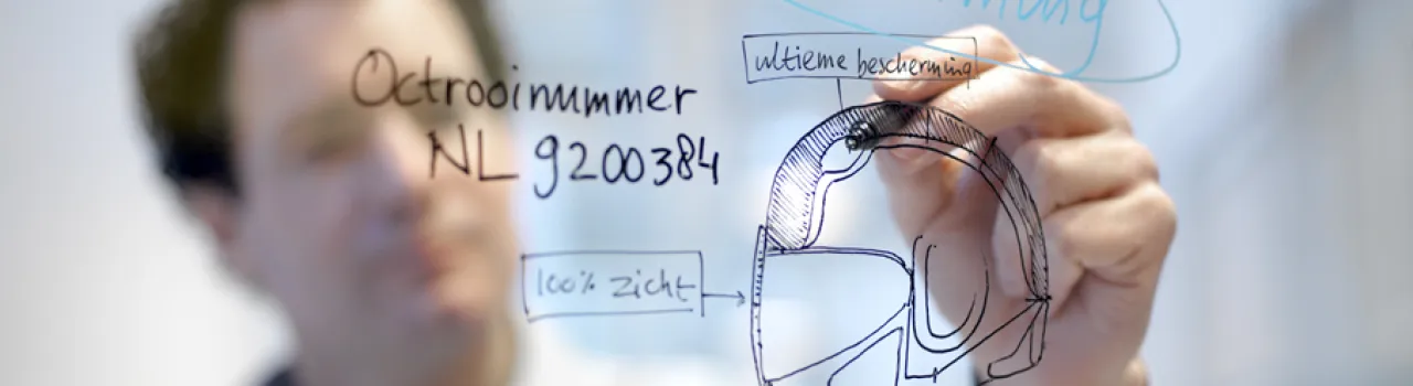 Man tekent op glazen wand. Te lezen zijn woorden 'bescherming' en 'octrooinummer'