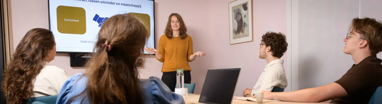Docent staat met presentatie in lokaal voor groepje studenten