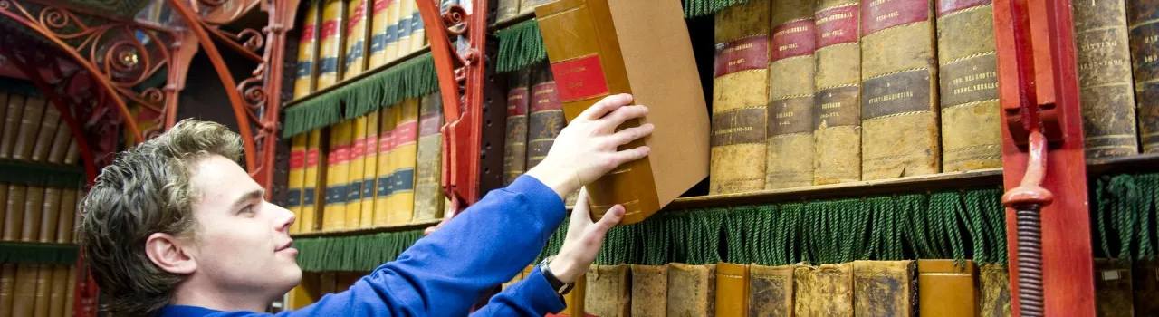Man pakt boek uit bibliotheek
