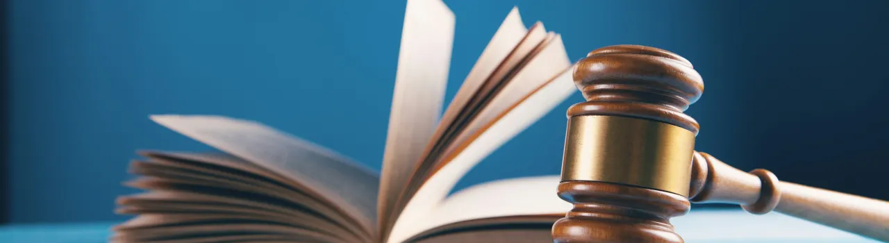 Houten rechterhamer met opengeslagen boek in de achtergrond