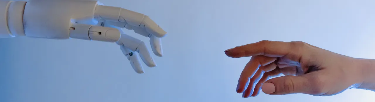 Robothand en menselijke hand reiken naar elkaar, zoals God en Adam in de schildering van Michelangelo