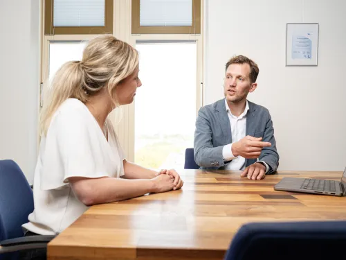 Adviseur in gesprek met klant. Op tafel staat een laptop
