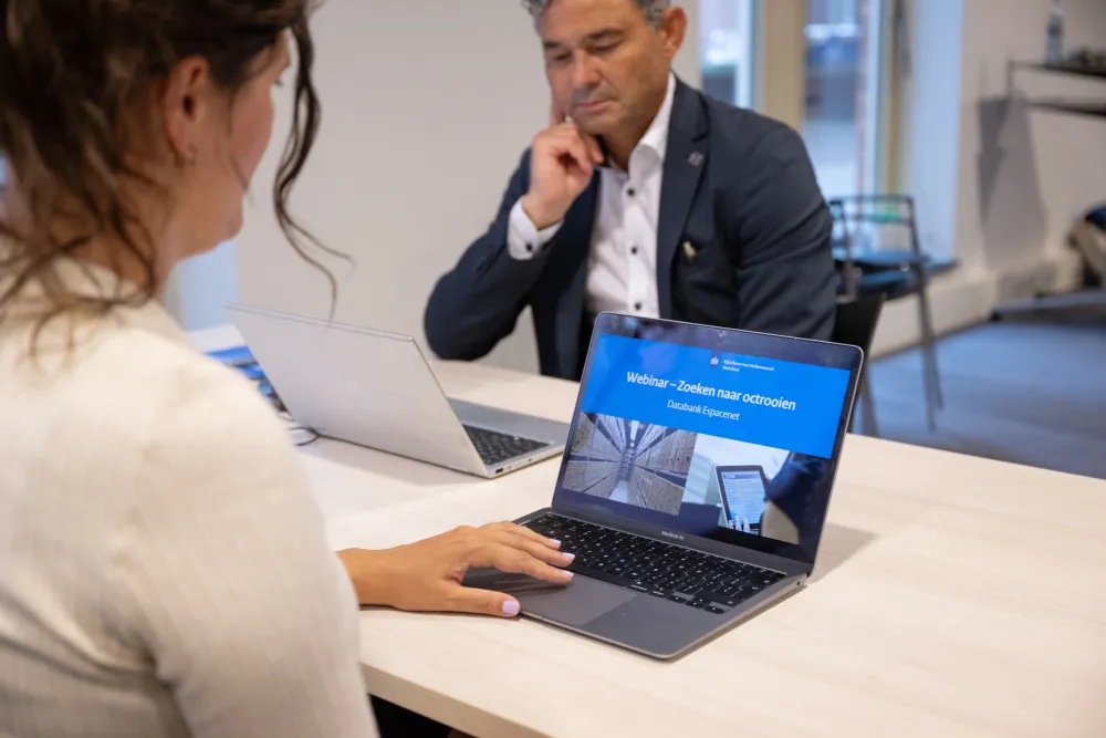 Vrouw achter laptop met daarop presentatie met tekst 'Webinar Zoeken naar octrooien: Databank Espacenet'